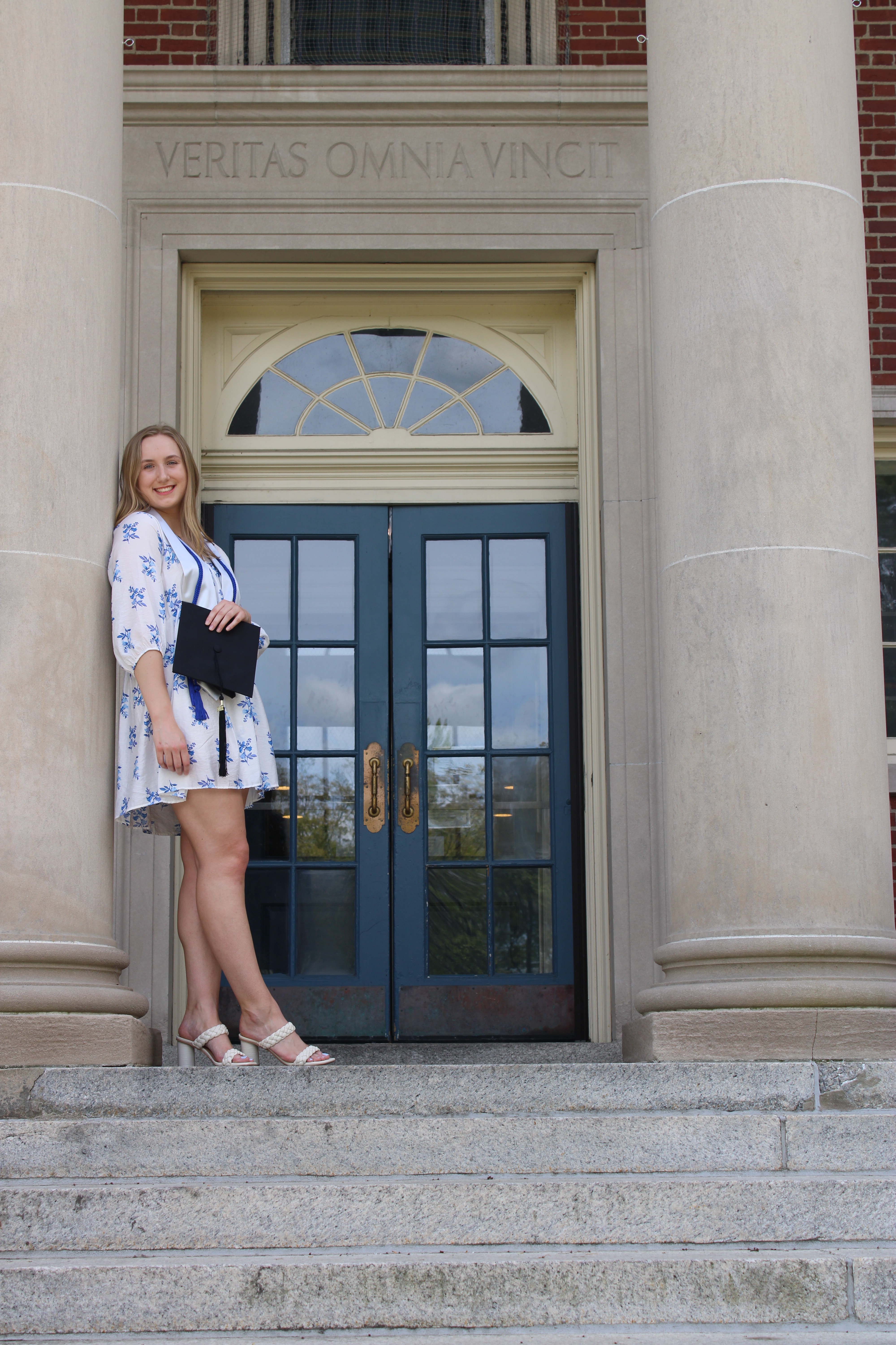 College graduate posing in front of academic building.