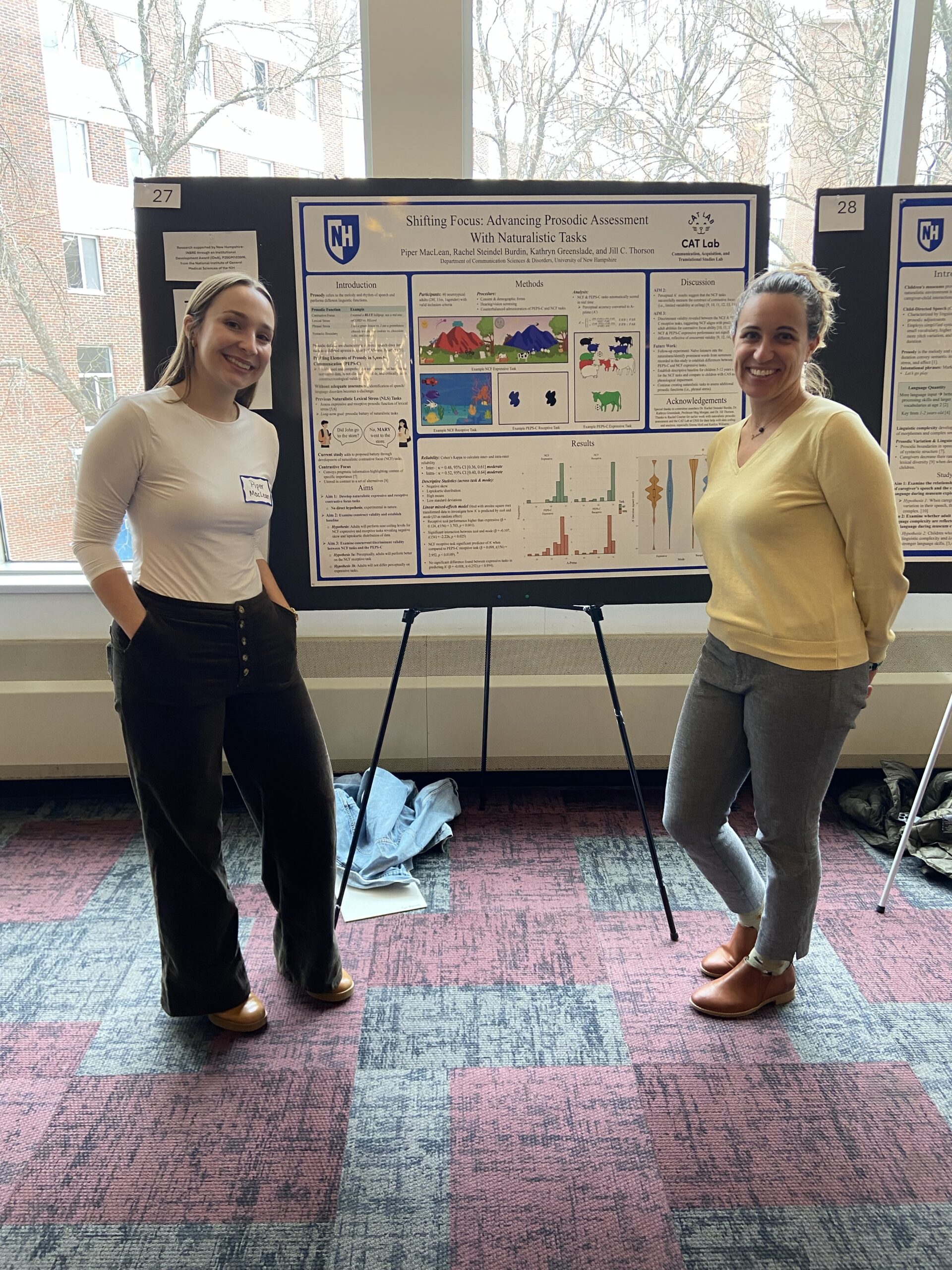 Two presenters standing in front of poster presentation.
