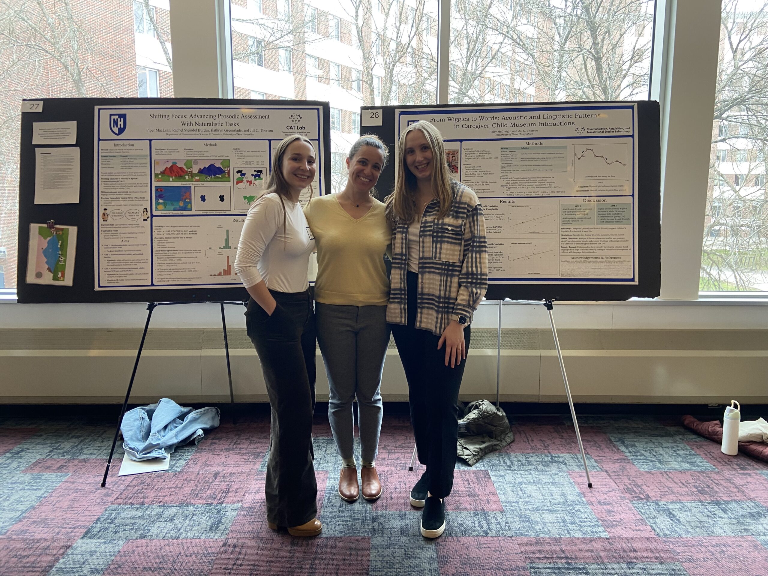 Three presenters standing in front of poster presentation.