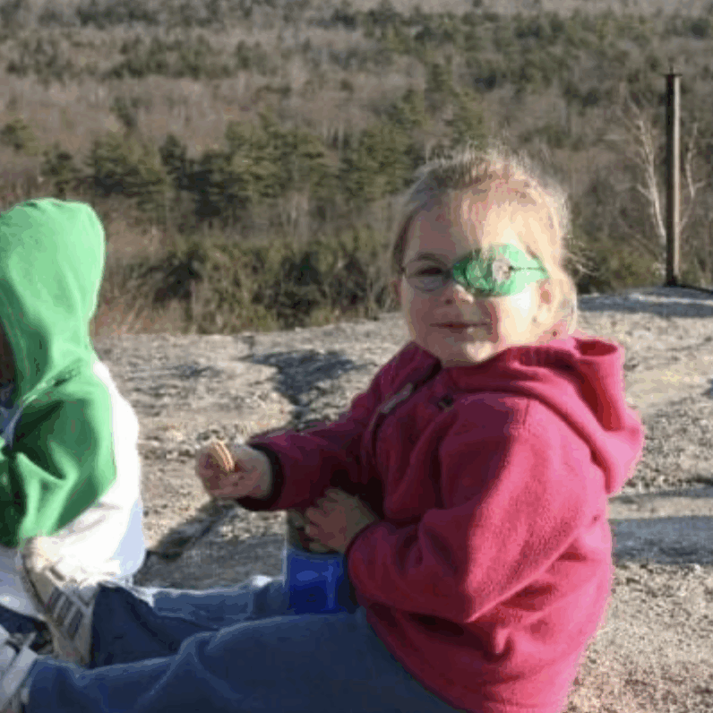 Little girl sitting at the top of a mountain.