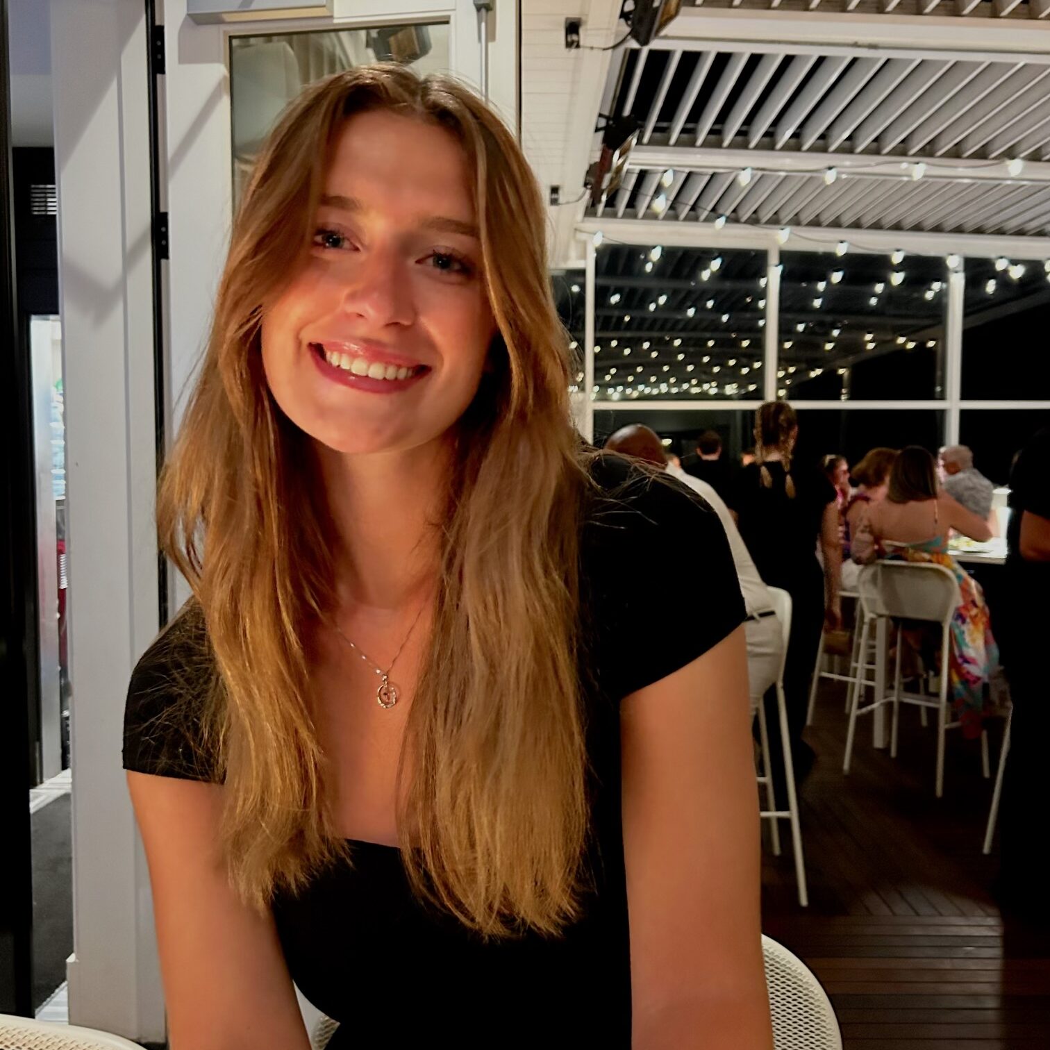 College-aged girl smiling at dinner.
