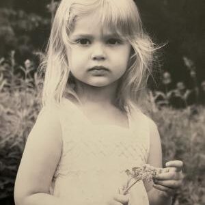 Little girl posing holding a flower.