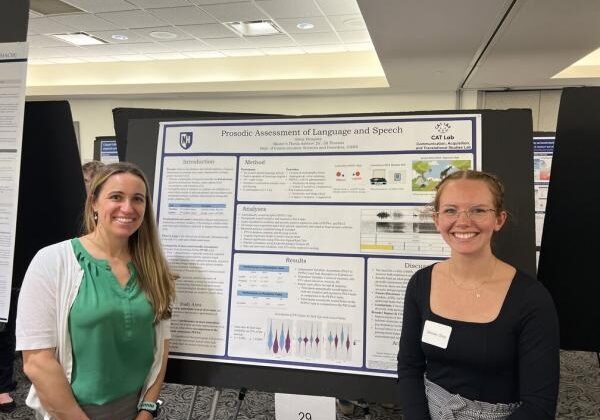 Two presenters standing in front of poster presentation.