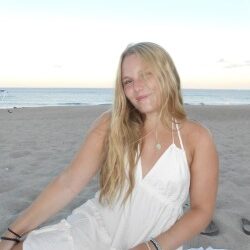 College-aged girl sitting and posing on the beach.
